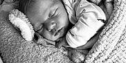 Elisabeth is registered to the contest to win money with this photo: baby, sleeping, blanket, plush_toy, unicorn, soft_texture, cozy, infant, child, cute, monochrome, portrait, peaceful, wrapped, sleep, resting, indoors, toddler, warm, comfort