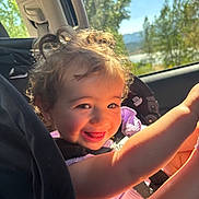 Brexlee joined the competition — help win amazing prizes! toddler, child, car_seat, smiling, curly_hair, sunlight, window, trees, mountains, car_interior, happy, portrait, seatbelt, playful, daylight, nature, face, person, clothing, travel