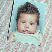 Amadeo participe au concours pour gagner de l'argent avec cette photo : baby, infant, printed_photo, portrait, face, eyes, chubby_cheeks, hair, tank_top, striped_background, fabric, closeup, photograph, paper, lying_flat, cute, studio_backdrop, small_photo, skin, expression
