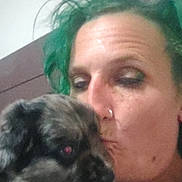 Marble is registered to the contest to win money with this photo: person, dog, green_hair, kiss, affection, indoor, casual, portrait, closeup, holding, pet, animal, human, face, love, candid, blurred, dim_light, nose_ring, shirt