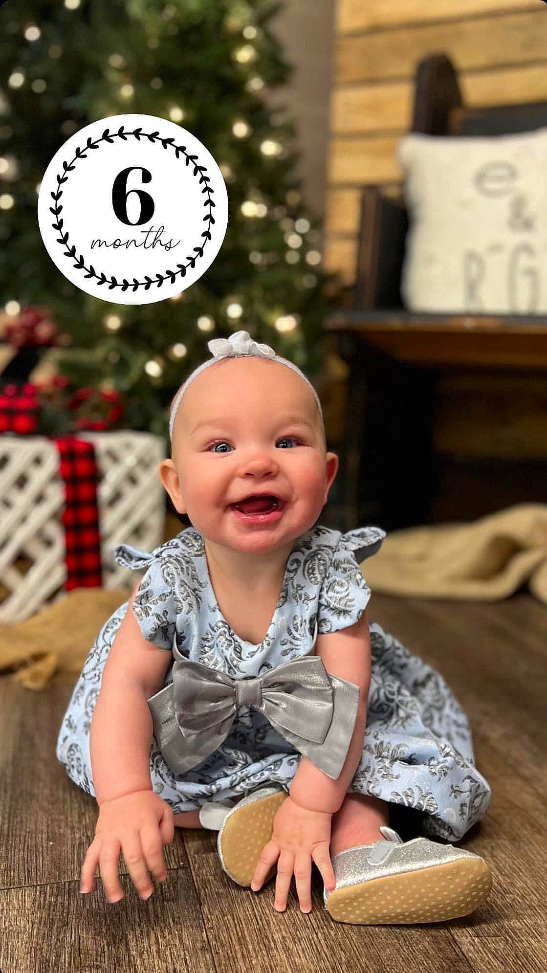 Brinley is registered to the contest to win money with this photo: baby, baby_toddler_clothing, cheek, child, christmas_decoration, christmas_tree, event, facial_expression, flooring, fun, happy, holiday, joy, person, photograph, sitting, skin, sleeve, smile, snapshot