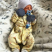 Remmi is registered to the contest to win money with this photo: newborn, baby, pacifier, mittens, hat, pajamas, sleeping, blanket, soft, cozy, infant, striped, patterned, resting, cute, small, comfort, indoor, child, portrait