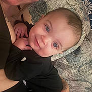 Silas is registered to the contest to win money with this photo: adult, affection, baby, black_clothing, closeup, couch, face, family, hand, happy, head, holding, home, indoor, patterned_fabric, person, portrait, skin, smile, tattoo