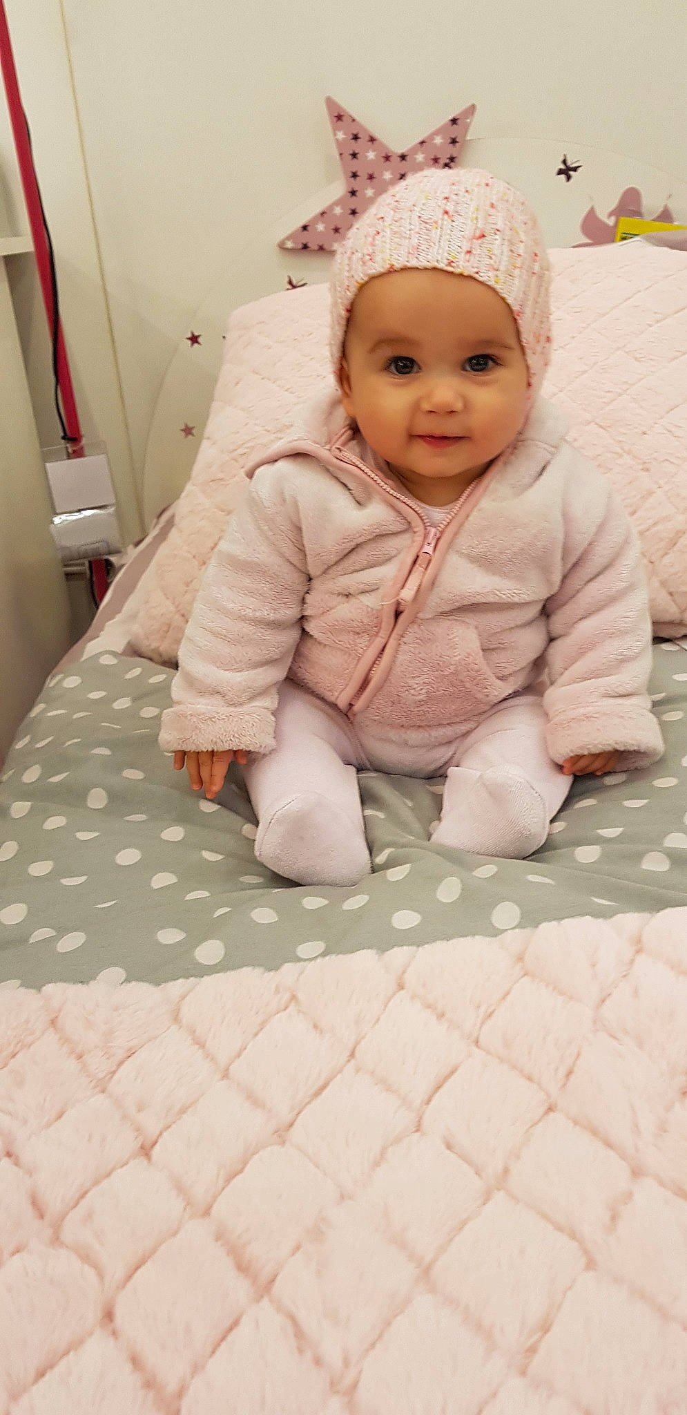 Emily a rejoint le concours — aidez-le/la à gagner de superbes lots ! baby, cheek, child, eye, floor, flooring, forehead, head, outerwear, person, pink, room, skin, smile, textile, toddler