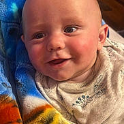 Kane is registered to the contest to win money with this photo: baby, smiling, blanket, blue, orange, face, infant, cute, portrait, closeup, indoors, child, happy, cozy, fabric, bedroom, person, skin, clothing, head