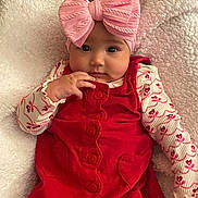 Claire joined the competition — help win amazing prizes! baby, child, infant, pink_bow, red_dress, blanket, cute, portrait, face, hand, soft_texture, cozy, young_child, clothing, headwear, lying_down, indoors, adorable, expression, person