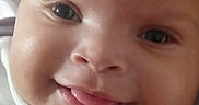 Kel'Lis is registered to the contest to win money with this photo: baby, infant, child, portrait, close_up, smiling, tongue_out, curly_hair, face, eyes, cheeks, lying_down, indoor, cozy, pillow, clothing, bib, calvin_klein, happy, photography