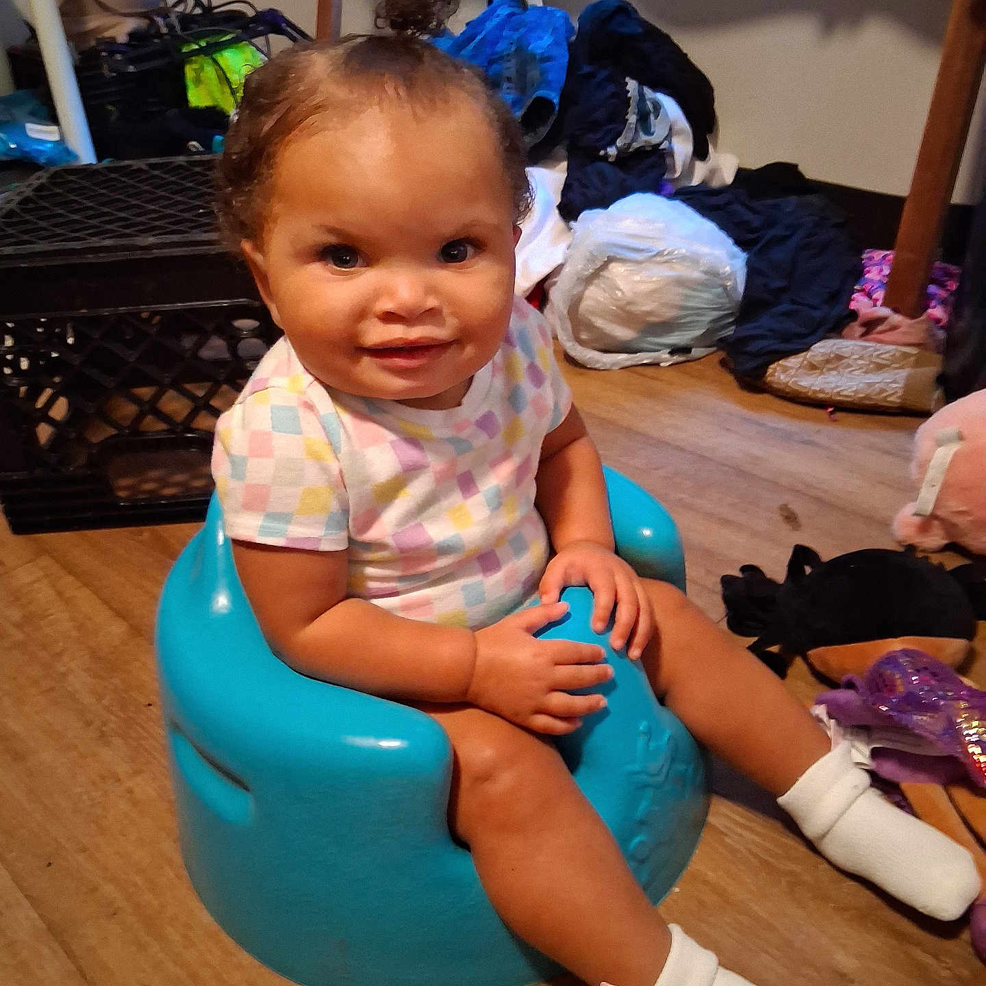 Kel'Lis is registered to the contest to win money with this photo: toddler, child, baby, sitting, smiling, portrait, indoors, booster_seat, turquoise_chair, pastel_clothing, striped_shirt, curly_hair, hair_bow, white_socks, wooden_floor, laundry, clothes, toys, household, happy