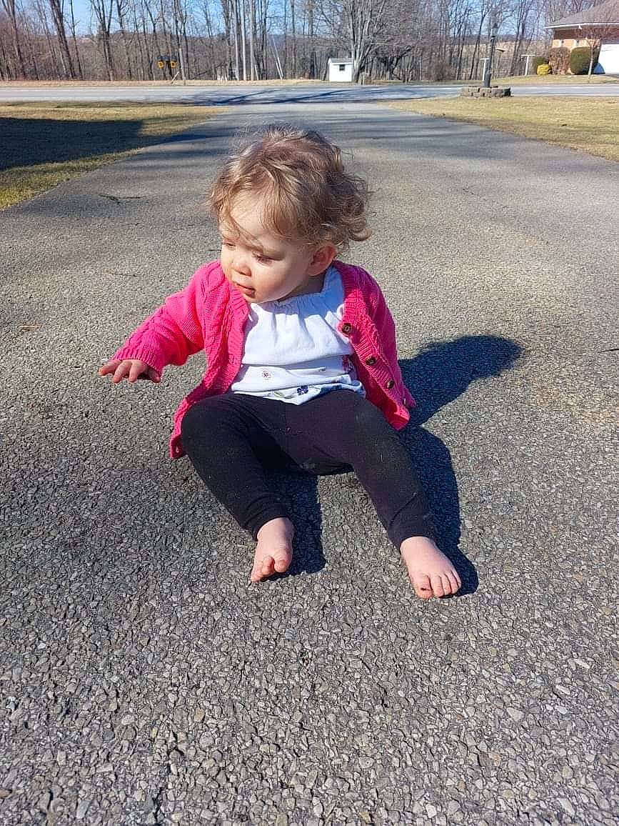 Melissa is registered to the contest to win money with this photo: asphalt, baby, baby_toddler_clothing, child, eye, fun, grass, human_body, leg, leisure, people_in_nature, person, plant, recreation, road_surface, sitting, sleeve, standing, tints_and_shades, toddler