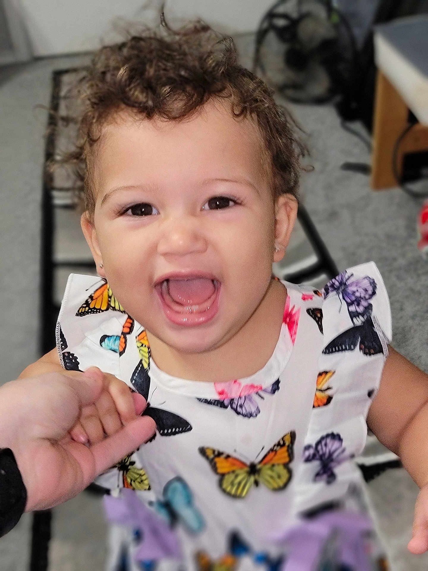 Brielle is registered to the contest to win money with this photo: child, toddler, smiling, happy, curly_hair, dress, butterfly_pattern, hand_holding, indoor, person, face, cute, joyful, earrings, closeup, portrait, bright, colorful, clothing, baby