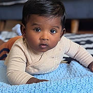 Bryan is registered to the contest to win money with this photo: baby, child, infant, blanket, blue, floor, rug, black_and_white, zigzag_pattern, couch, indoor, curious, looking, face, person, clothing, long_sleeve, hand, flooring, home