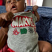 Keyshawn joined the competition — help win amazing prizes! baby, child, marvel, onesie, clothing, fist, hand, face, person, infant, cute, indoor, blanket, bed, skin, portrait, expression, holding, young, casual