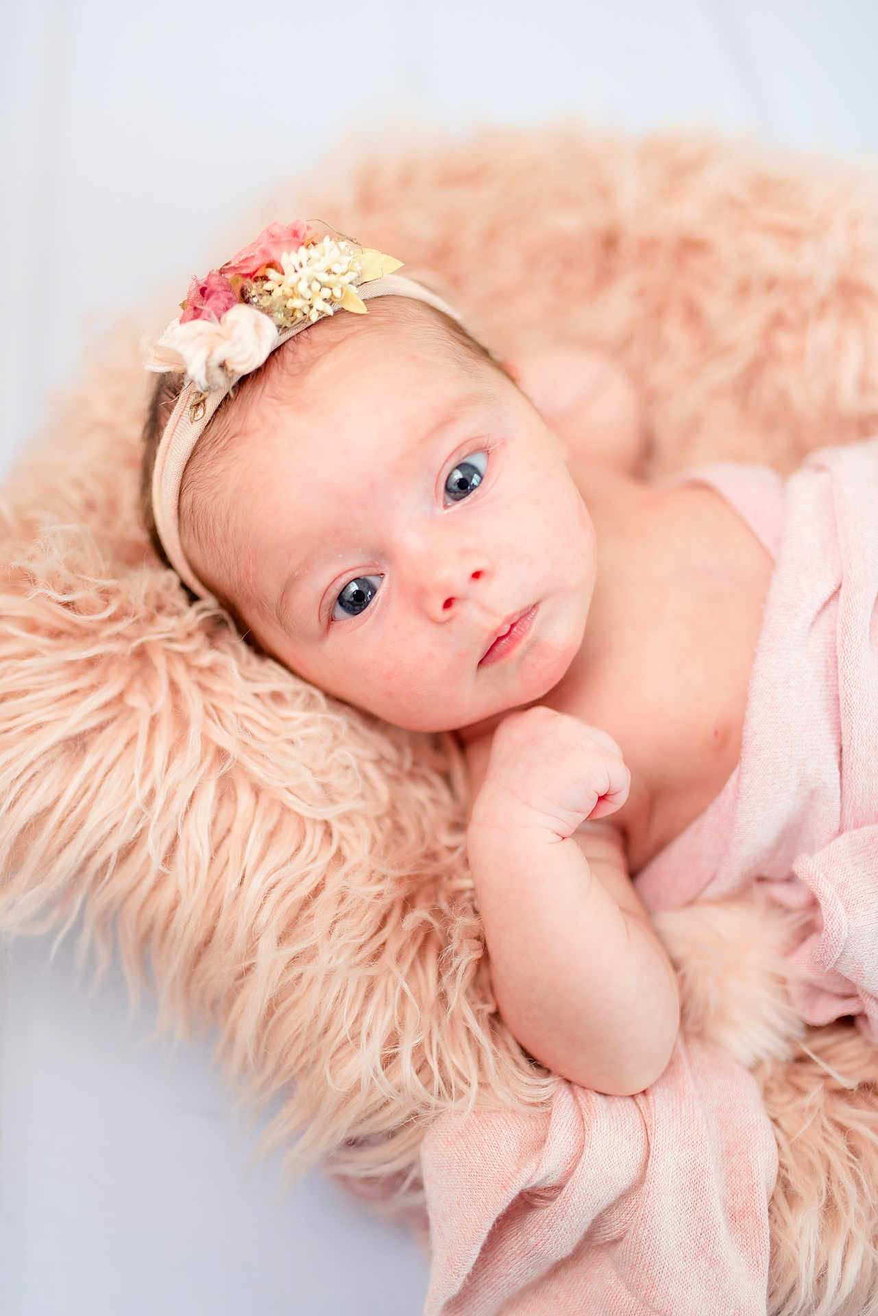 Kinley is registered to the contest to win money with this photo: baby, infant, face, headband, blue_eyes, blanket, cushion, soft_texture, pink, peach, skin, portrait, newborn, cute, child, lying_down, closeup, expression, indoors, resting