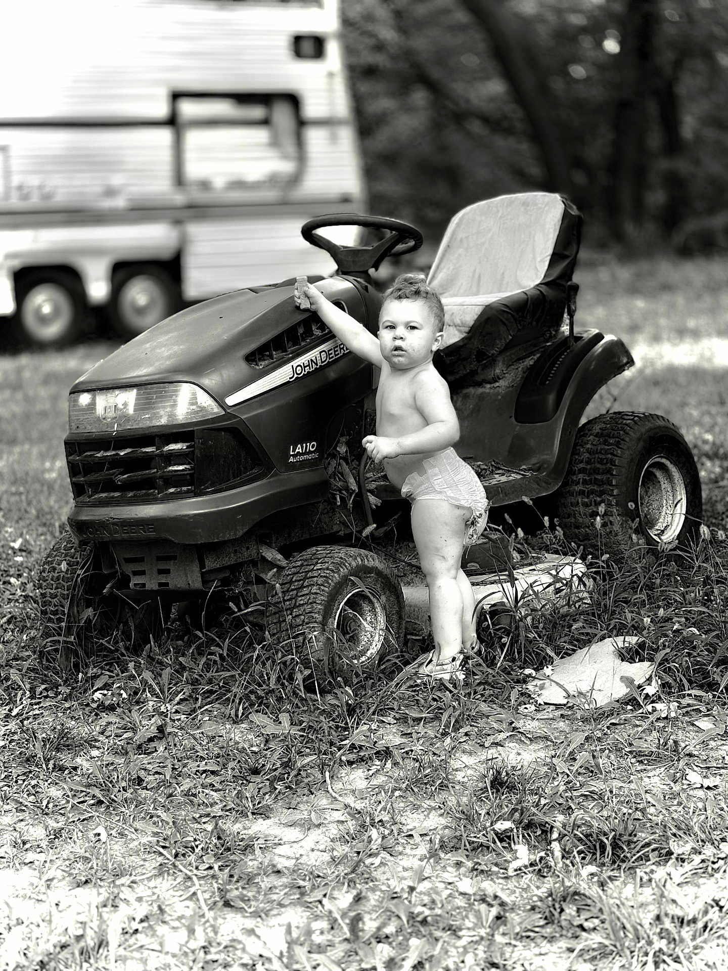 Atlus is registered to the contest to win money with this photo: toddler, child, lawn_tractor, john_deere, diaper, grass, outdoor, vehicle, black_and_white, nature, person, standing, summer, rural, small_child, play, curious, portrait, wheel, camper
