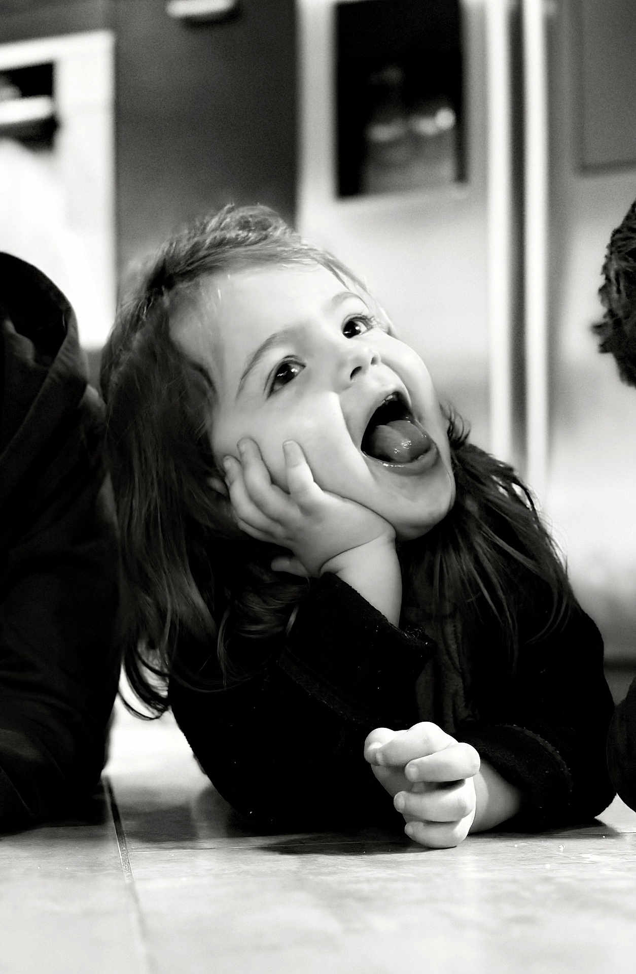 Emma a rejoint le concours — aidez-le/la à gagner de superbes lots ! child, black_and_white, happy, smiling, face, hands, floor, long_hair, portrait, indoor, expression, cute, joyful, person, young, playful, closeup, emotion, casual, candid