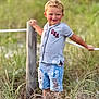Waylon is registered to the contest to win money with this photo: blond_hair, boy, casual_clothing, child, curly_hair, daylight, denim_shorts, grass, greenery, happy, nature, outdoor, portrait, ripped_shorts, rope, shirt, smiling, standing, summer, wooden_post