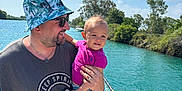 Emma participe au concours pour gagner de l'argent avec cette photo : man, child, toddler, boat, water, river, sky, trees, hat, sunglasses, smile, holding, summer, outdoor, nature, casual_clothing, netting, sunlight, happy, family