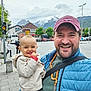 Emma a rejoint le concours — aidez-le/la à gagner de superbes lots ! baby, child, man, smile, street, sidewalk, traffic_light, mountains, clouds, trees, buildings, car, person, hat, jacket, urban, happy, outdoor, daytime, people