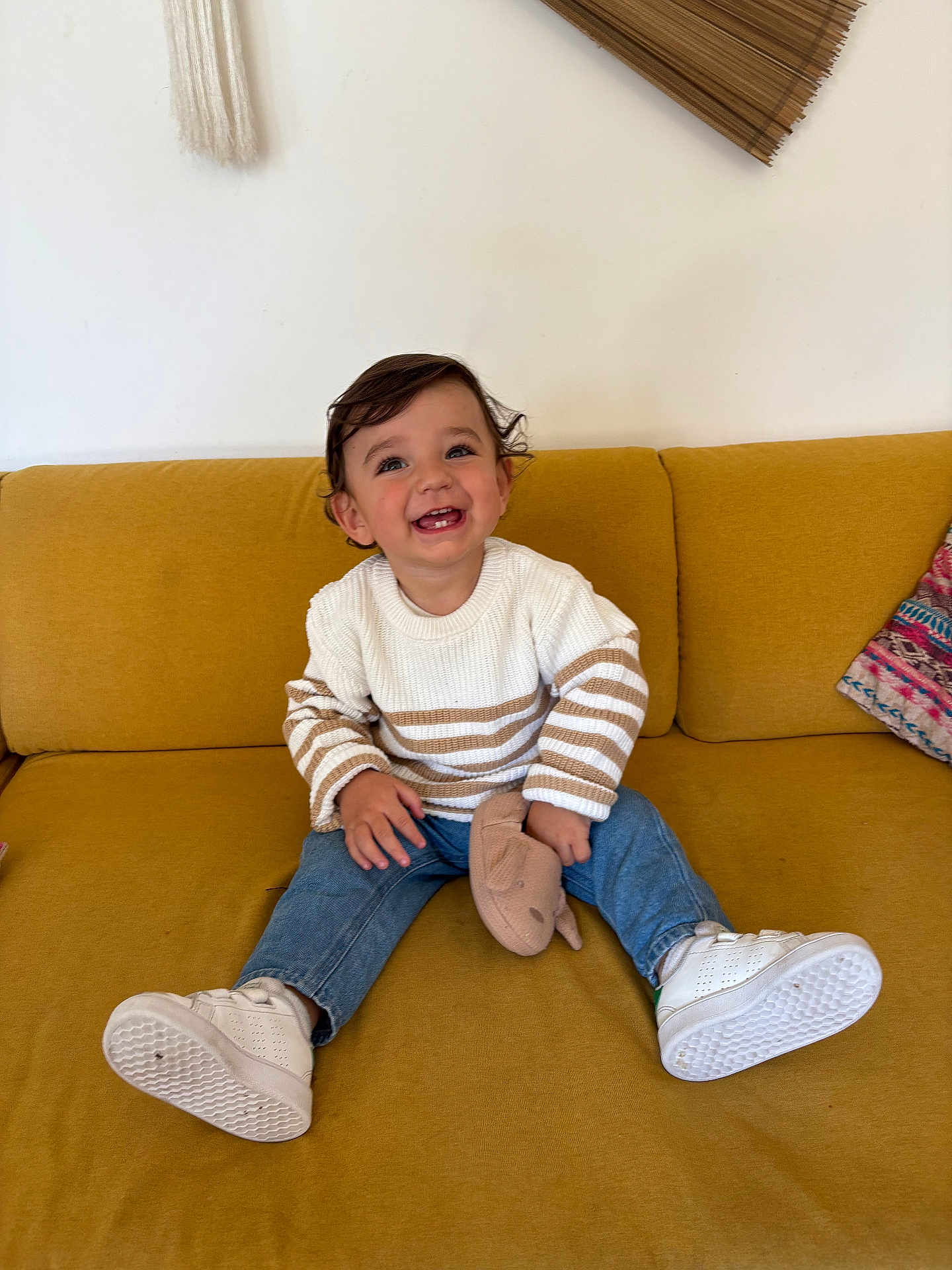 Lissandro a rejoint le concours — aidez-le/la à gagner de superbes lots ! toddler, child, smiling, sitting, couch, yellow_couch, white_sneakers, striped_sweater, blue_jeans, soft_toy, happy, indoor, curly_hair, cute, casual_clothing, playful, portrait, home, furniture, cozy