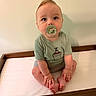 Clay is registered to the contest to win money with this photo: baby, barefoot, carrot_graphic, changing_table, child, clothing, cross_legged, curious_eyes, cute, green_shirt, hands, indoor, infant, light_skin, neutral_background, pacifier, portrait, short_hair, sitting, wooden_furniture