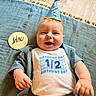 baby, child, infant, smiling, birthday, party_hat, clothing, blue_blanket, happy, laying_down, indoors, cute, celebration, half_birthday, toddler, shirt, pants, hand, face, head