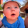 baby, child, face, cap, hat, blue_shirt, outdoor, portrait, curious, wide_eyes, skin, person, infant, expression, close_up, daylight, headwear, cute, drool, young