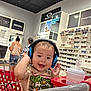 Bryan joined the competition — help win amazing prizes! child, toddler, headphones, shopping_cart, baby_bottle, eyeglasses, store_interior, retail, people, smile, clothing, person, shopping, indoor, product_display, accessories, retail_store, happy, cute, casual