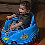 Bryan is registered to the contest to win money with this photo: blue, child, clothing, couch, hands, happy, happy_face, indoor, lighting, play, red_lights, seat, short_hair, smiling, sneakers, toddler, toy_car, vehicle, wooden_floor, young_child