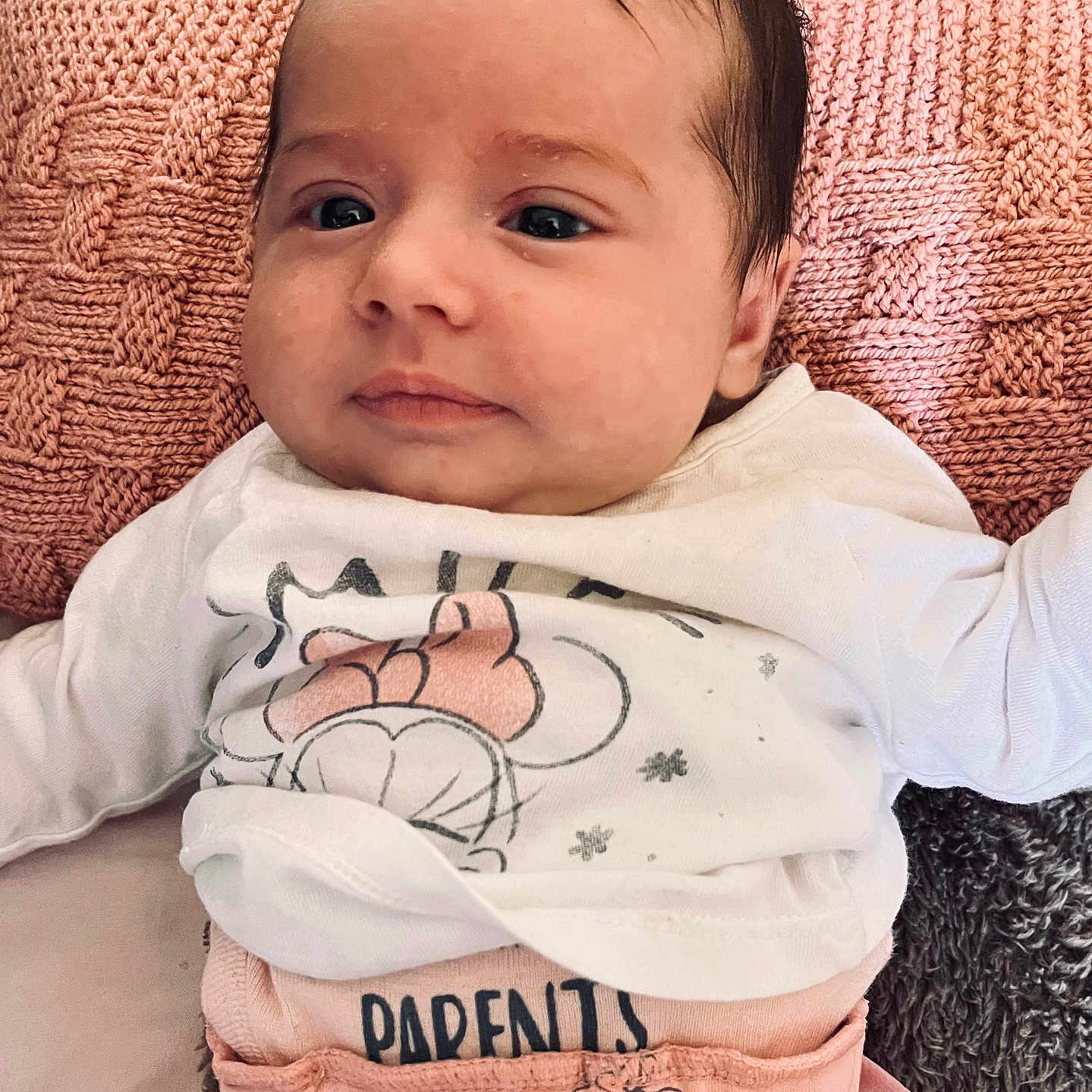 Rosana a rejoint le concours — aidez-le/la à gagner de superbes lots ! apparel, baby, child, clothing, comfortable, cushion, cute, expression, eyes, face, indoors, infant, lying_down, newborn, person, pink, portrait, soft, texture, white