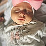 baby, sleeping, pink_bow, headwear, cute, infant, clothing, minnie_mouse, white_shirt, face, closeup, peaceful, child, adorable, soft_light, indoor, portrait, resting, knitted_cap, young_child