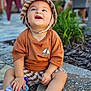 toddler, child, baby, hat, bucket_hat, smiling, happy, outdoor, pavement, snack_pouch, clothing, shorts, person, greenery, blurred_background, sitting, cute, sunlight, casual, summer