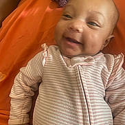 Jaliyah Aka Cookie is registered to the contest to win money with this photo: baby, infant, child, smiling, portrait, face, eyes, indoors, orange_background, baby_clothing, striped_outfit, pink, lying_down, happy, adorable, close_up, head, arms, photography, cozy