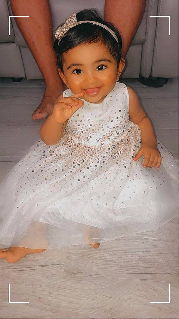 Arya participe au concours pour gagner de l'argent avec cette photo : baby_toddler_clothing, child, clothing, day_dress, dress, embellishment, facial_expression, finger, floor, flooring, hair_accessory, happy, headpiece, human_body, joy, one_piece_garment, person, pink, skin, textile