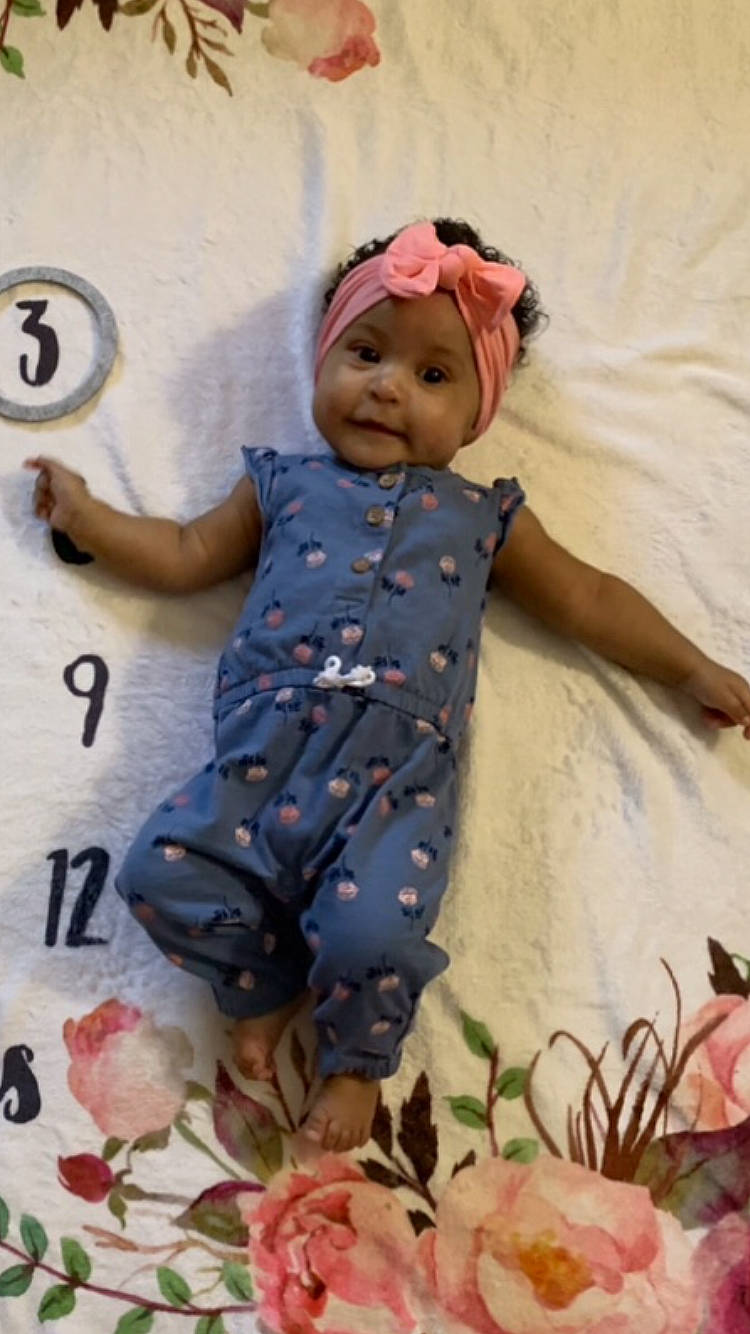 Anaya is registered to the contest to win money with this photo: baby, baby_toddler_clothing, child, facial_expression, finger, fun, happy, headwear, linens, magenta, mammal, pattern, people_in_nature, person, petal, pink, plant, sleeve, smile, textile