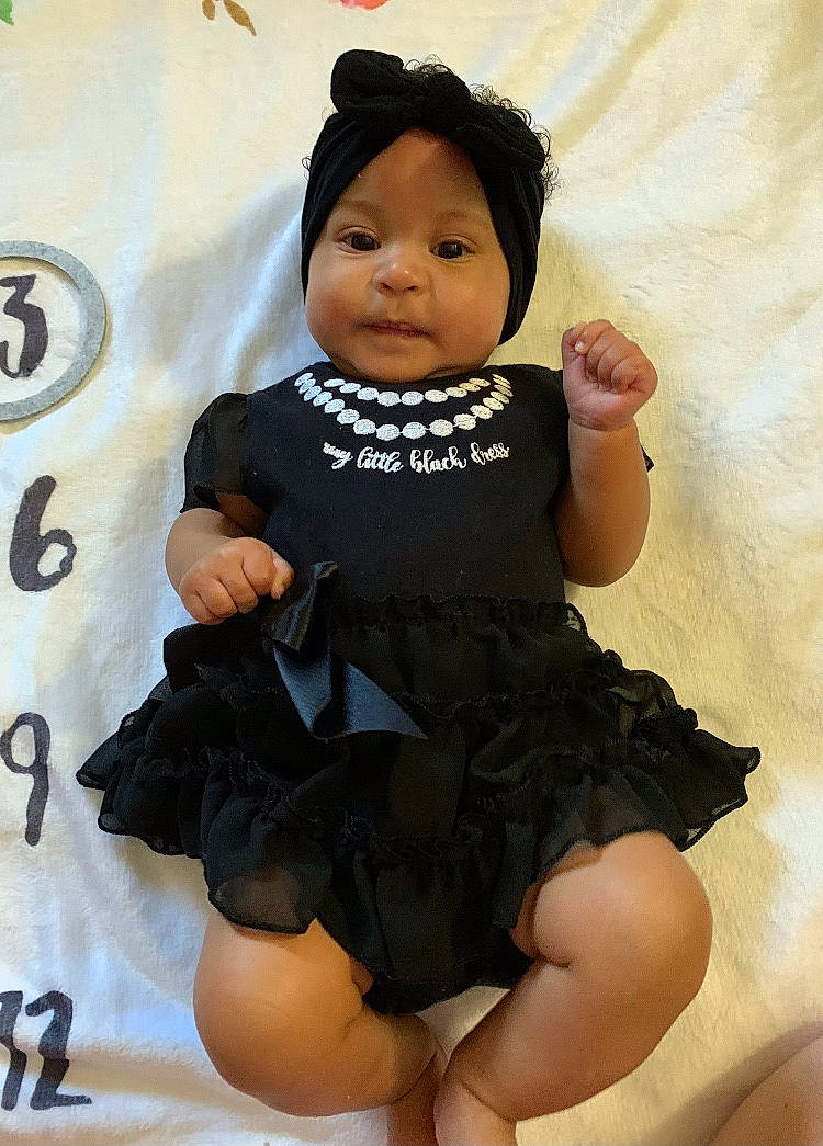 Anaya is registered to the contest to win money with this photo: arm, baby_toddler_clothing, black_hair, cheek, day_dress, dress, face, fashion_design, finger, happy, head, human_body, human_leg, leg, one_piece_garment, pattern, person, sleeve, thigh, thumb