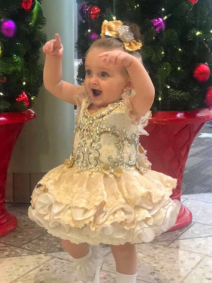 Abbigail is registered to the contest to win money with this photo: child, christmas, christmas_decoration, christmas_tree, dress, person, pink, smile, toddler