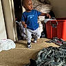 Antonio is registered to the contest to win money with this photo: toddler, child, blue_tshirt, sweatpants, sneakers, indoor, carpet, laundry, plastic_bin, blanket, doorway, curious, walking, clutter, room, cable, plaid, sock, person, home