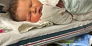 Arizona is registered to the contest to win money with this photo: newborn, baby, sleeping, blanket, hospital, bassinet, towel, hand, face, infant, clothing, bed, healthcare, patient, rest, cozy, cute, peaceful, skin, hospital_room