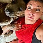 Puppy Or Pepsi joined the competition — help win amazing prizes! person, dog, tattoo, lip_piercing, red_top, mattress, indoor, close_up, face, snuggling, curious_dog, casual, relaxed, human, pet, friendship, expression, skin, arm, candid