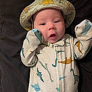Harlan joined the competition — help win amazing prizes! baby, infant, dinosaur_pattern, onesie, hat, sleepwear, cute, face, hand, lying_down, blanket, child, portrait, closeup, apparel, headwear, expression, skin, sleeping_area, cozy