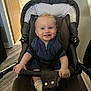 baby, stroller, indoor, child, smile, blue_eyes, clothing, seat, socks, handlebar, floor, door, happy, person, infant, cushion, hair, grip, young_child, portrait