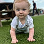 baby, child, crawling, grass, outdoor, curly_hair, blue_eyes, overalls, white_shirt, person, blurred_background, picnic_table, daylight, innocence, exploration, cute, portrait, hands, knees, focus