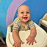 Silas joined the competition — help win amazing prizes! baby, child, high_chair, smiling, happy, indoor, colorful_background, rainbow, wall_painting, infant, clothing, person, portrait, cute, hands, face, young_child, seated, feeding_chair, playful