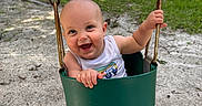 Silas joined the competition — help win amazing prizes! baby, child, swing, playground, sand, greenery, smile, happy, outdoor, summer, bucket_swing, metal_chains, tank_top, barefoot, infant, fun, daylight, park, nature, joy