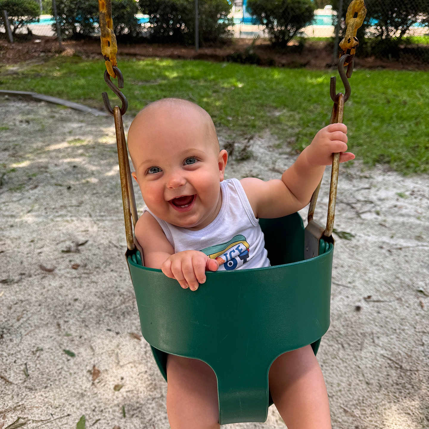 Silas joined the competition — help win amazing prizes! baby, child, swing, playground, sand, greenery, smile, happy, outdoor, summer, bucket_swing, metal_chains, tank_top, barefoot, infant, fun, daylight, park, nature, joy