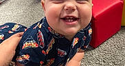 Silas is registered to the contest to win money with this photo: baby, carpet, child, clothing, colorful, cute, face, floor, green_block, hand, happy, hot_dog_print, indoor, infant, person, playtime, red_block, smiling, toy_block, yellow_block