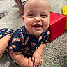 Silas is registered to the contest to win money with this photo: baby, smiling, carpet, child, indoor, colorful, clothing, hot_dog_print, toy_block, red_block, yellow_block, green_block, hand, face, person, cute, happy, infant, playtime, floor