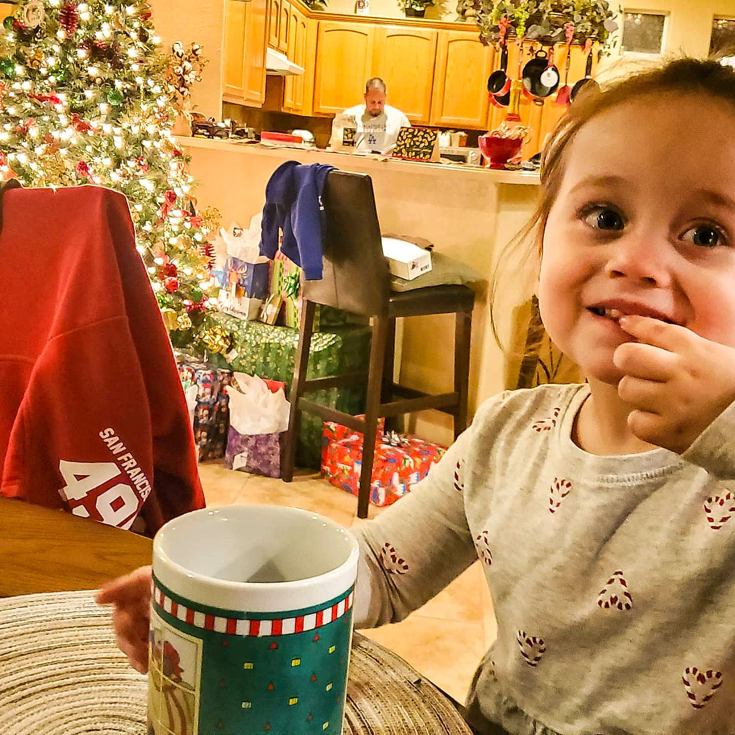 Addalynn is registered to the contest to win money with this photo: baby, baby_toddler_clothing, cabinetry, christmas, christmas_decoration, christmas_eve, christmas_ornament, christmas_tree, conifer, cup, drinkware, fir, holiday, holiday_ornament, houseplant, interior_design, joy, ornament, person, pine