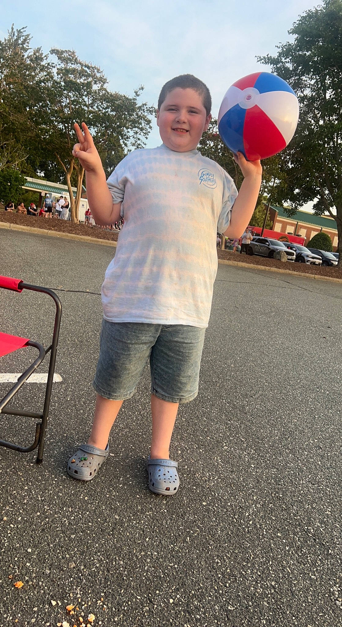 Tyson is registered to the contest to win money with this photo: asphalt, chair, child, electric_blue, fun, happy, human_leg, joy, leg, leisure, party_supply, person, play, recreation, road, road_surface, shorts, sky, standing, t_shirt