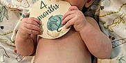 Cain is registered to the contest to win money with this photo: baby, infant, diaper, blanket, dinosaur, card, milestone, cute, cheeks, hand, face, lying_down, skin, eyes, mouth, fingers, soft, child, portrait, indoors